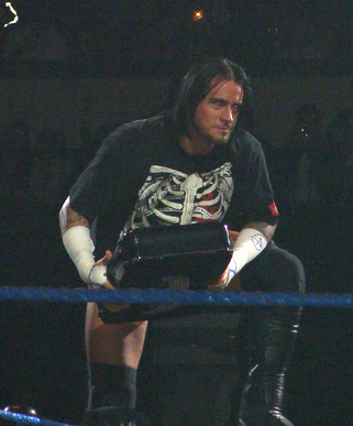 a male wrestler with a skeleton shirt sitting in the ring