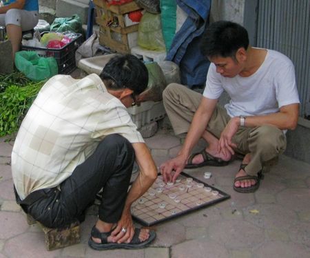 two young men sitting around playing with a tile