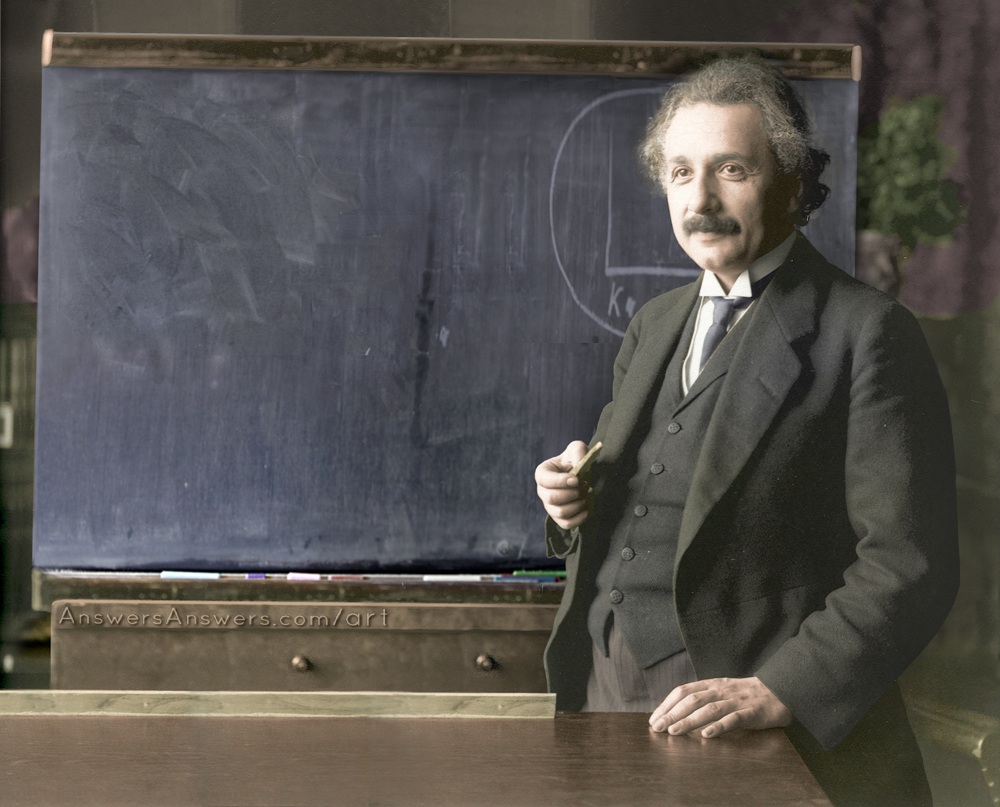 a man is holding a pen standing in front of a blackboard