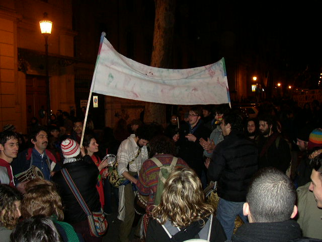 many people standing around in the dark and some are holding flags