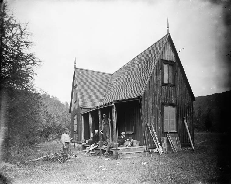 a black and white po of men standing outside a house