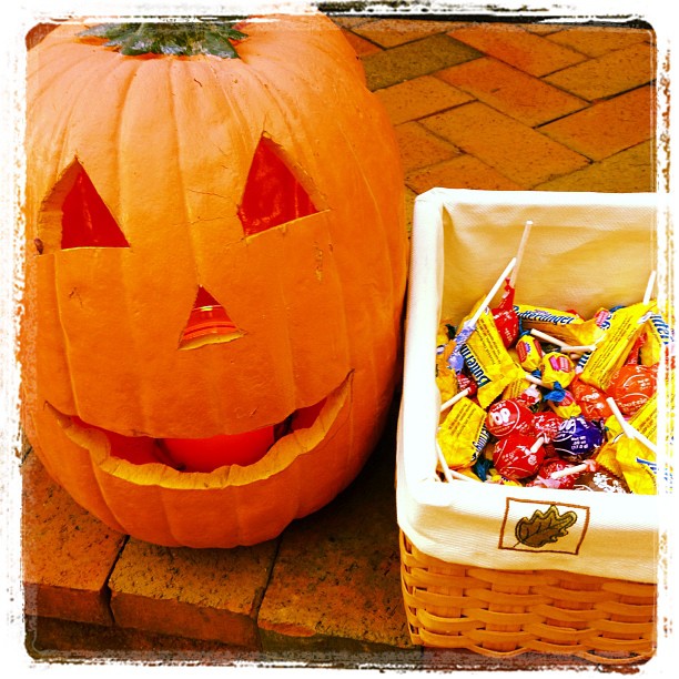 a pumpkin next to a basket of candy with the eyes painted