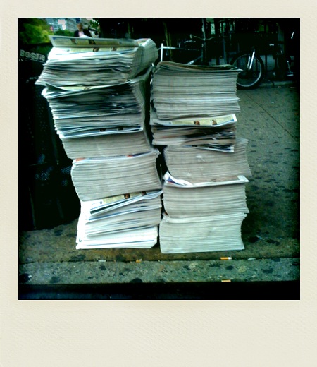 stack of newspapers sitting on a side walk