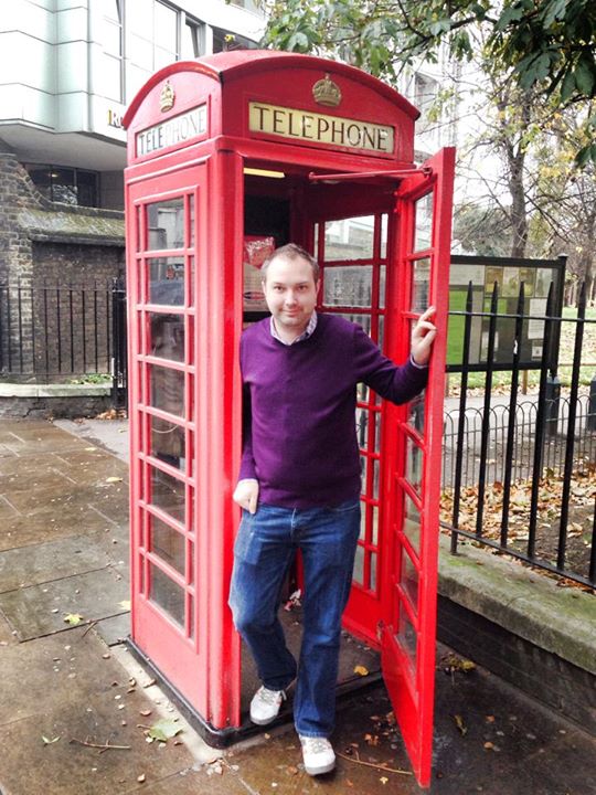 a man standing in a red telephone booth