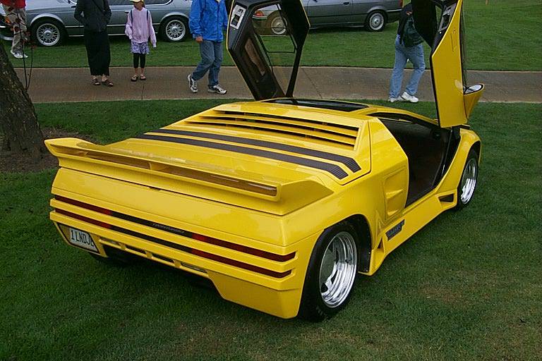 a yellow lambr - car sits parked on some grass