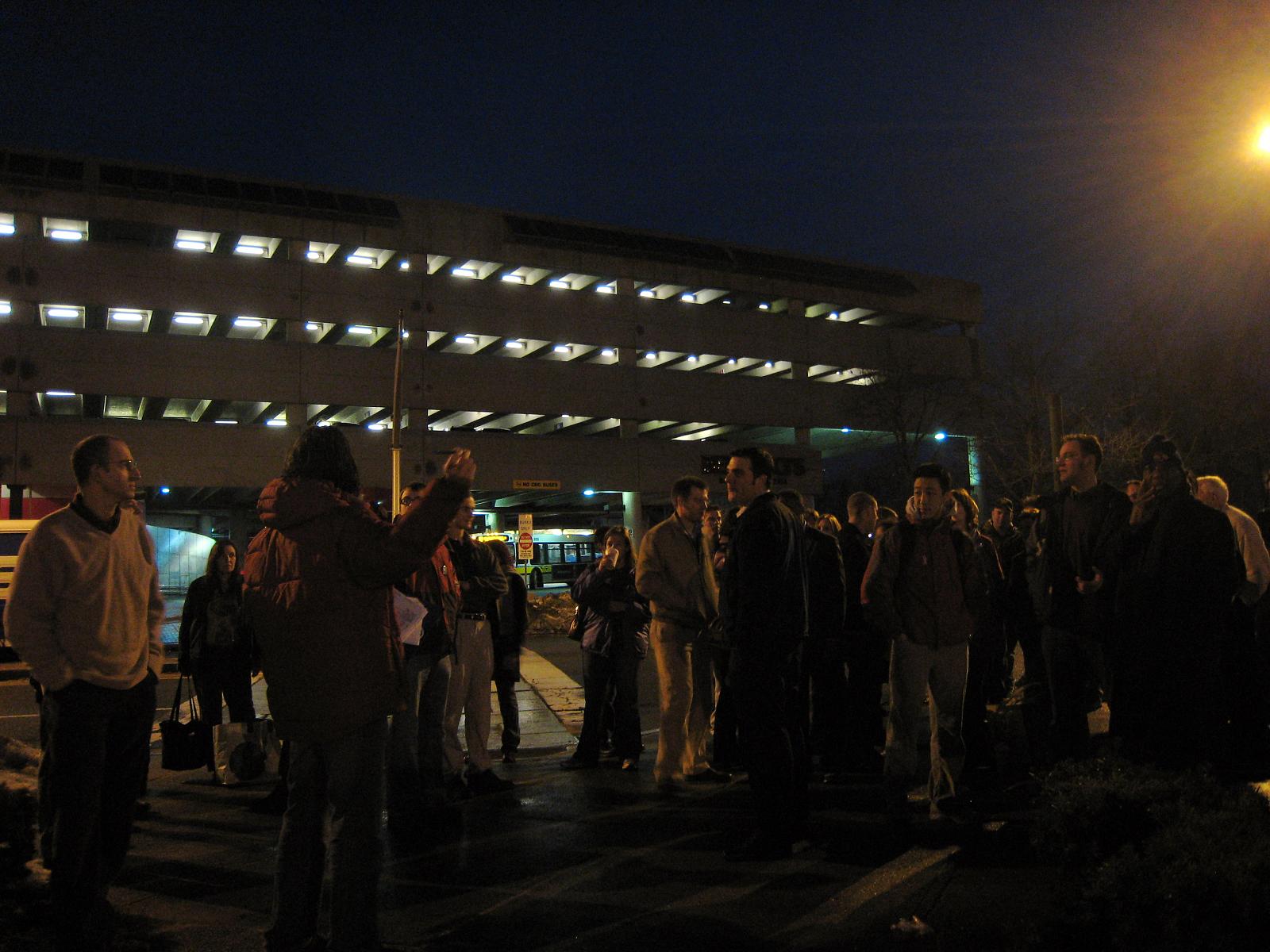 people standing around each other on a city street at night