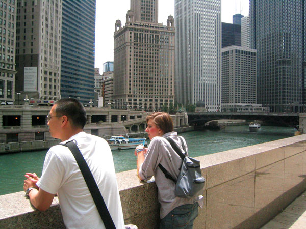 a couple standing by a railing next to buildings in the background