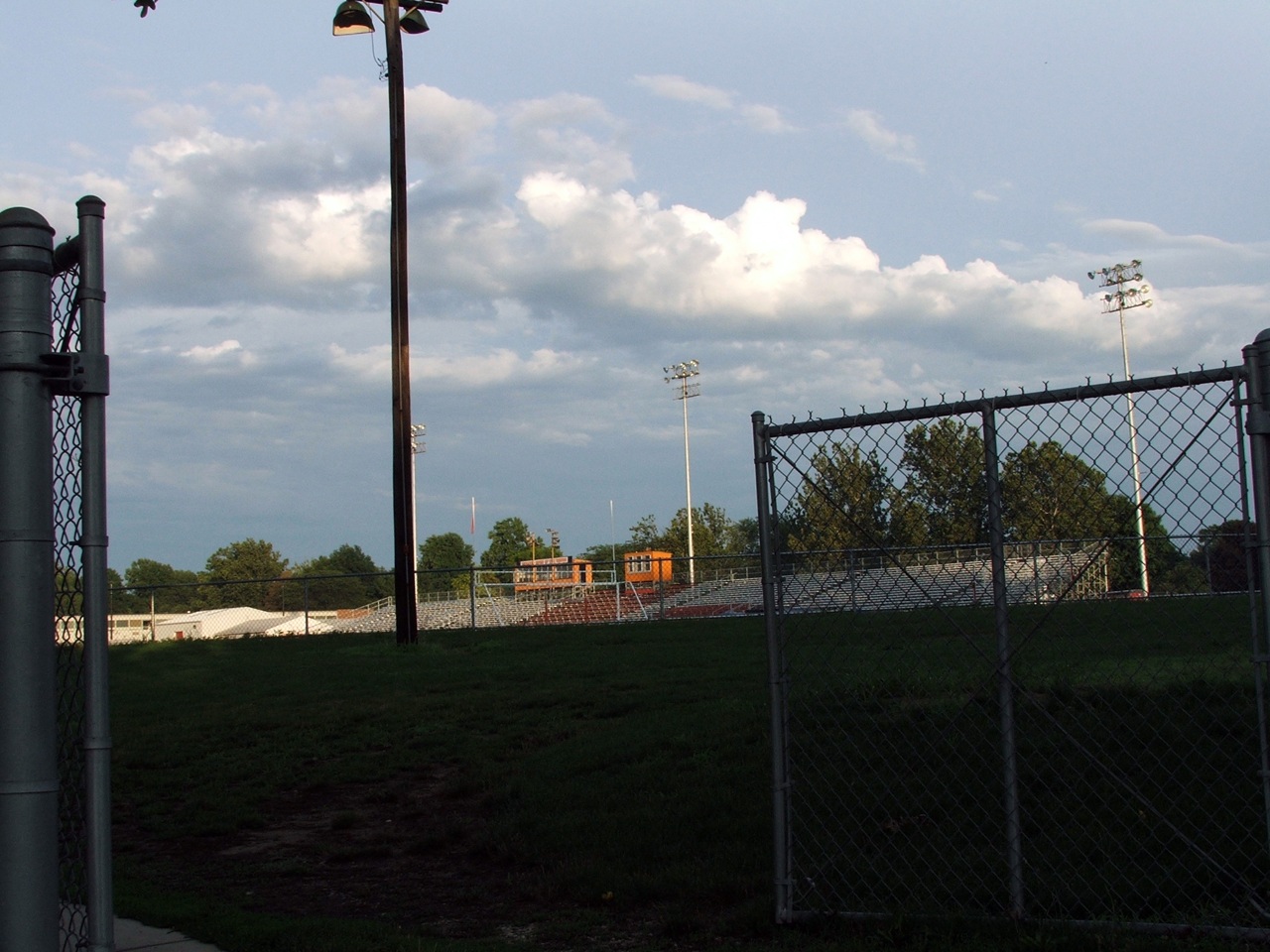 a fenced in field next to tall buildings