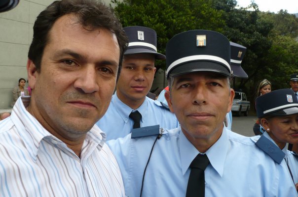 two men standing next to each other with a group of policemen in the background