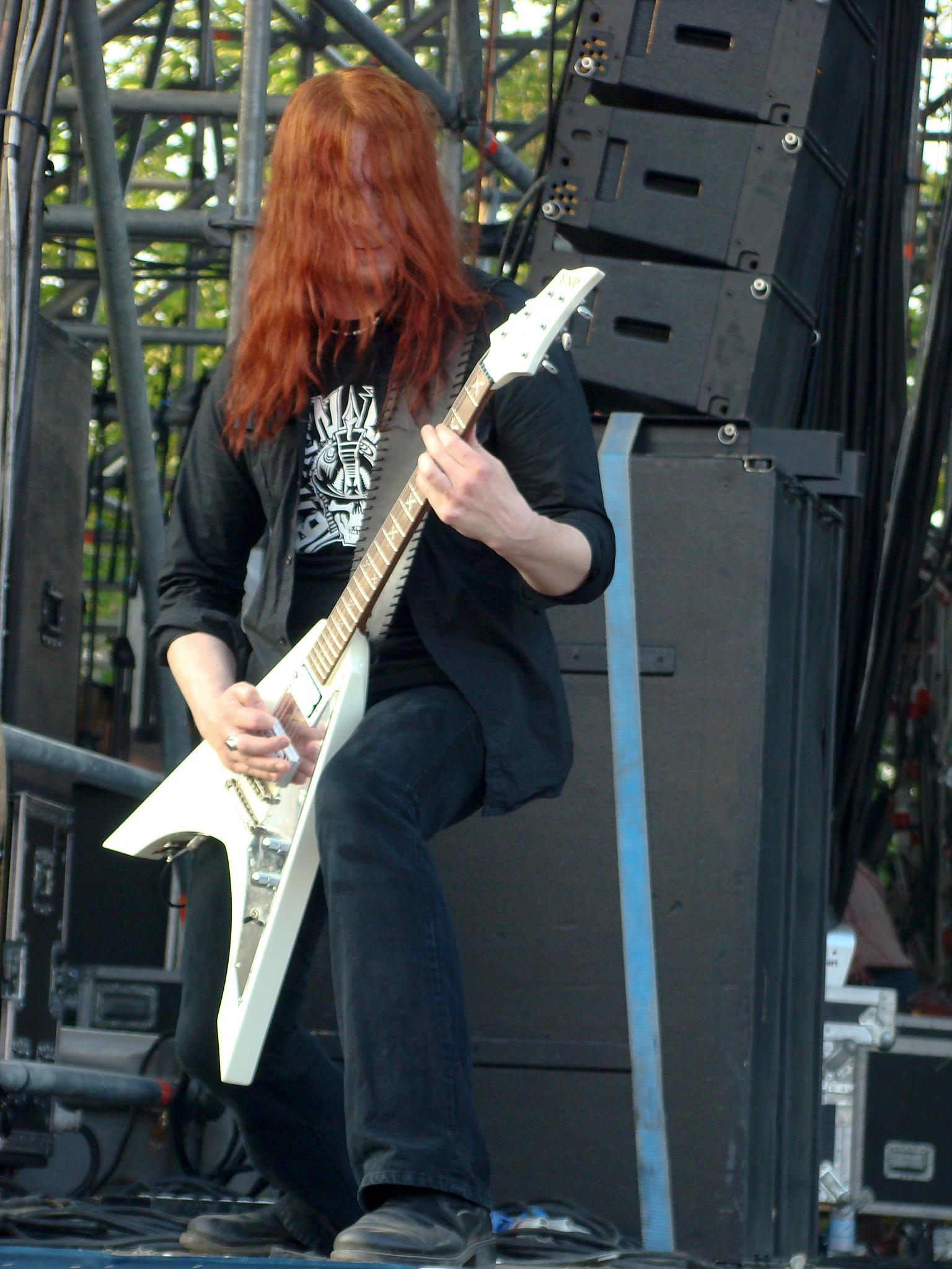 red - headed guitarist with long hair plays guitar on stage