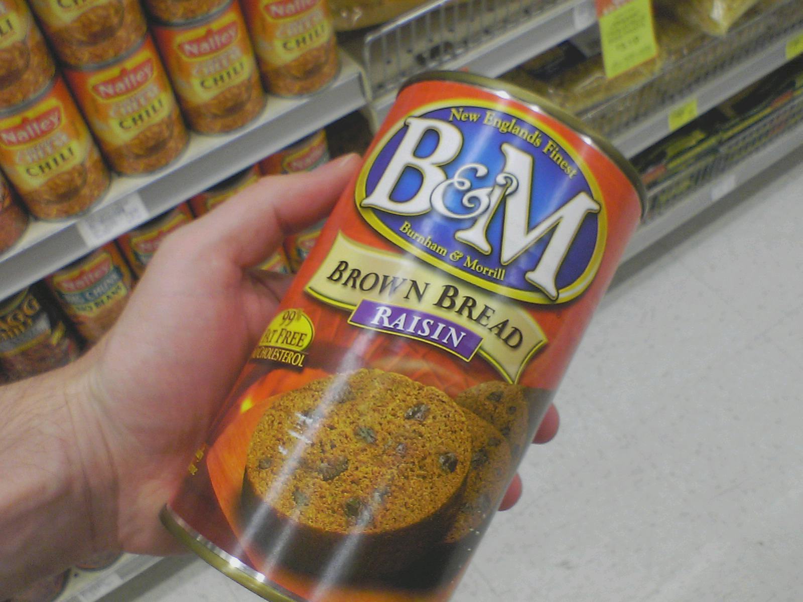 a hand holding a can of b & m coffee at a store