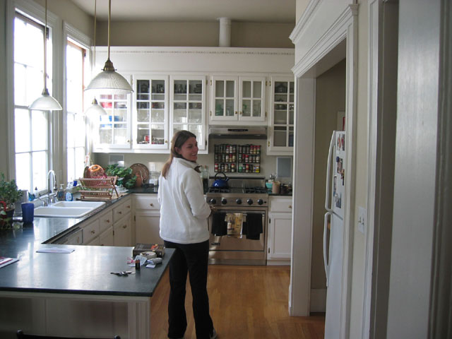 a woman stands at the edge of the kitchen counter in front of the sink