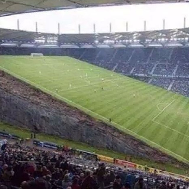 a large stadium full of people with one of the stands on a cloudy day