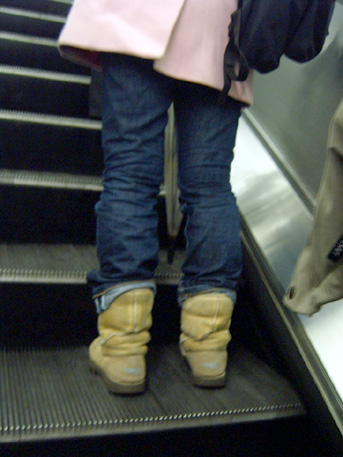 a woman in yellow boots standing on an escalator