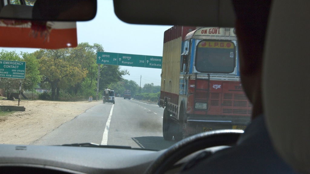 a view from the back seat of a vehicle driving down a road with the door handle down