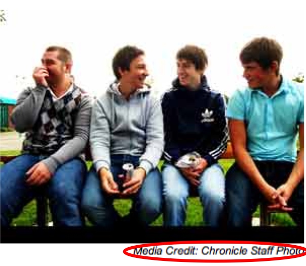 four men laughing while sitting together on a bench