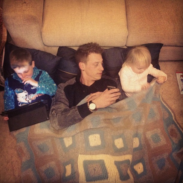 a man sitting with two small boys on the couch