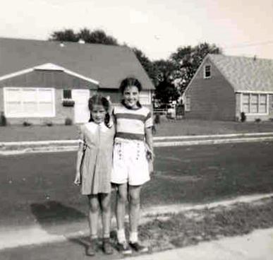 two s in dresses standing outside with buildings