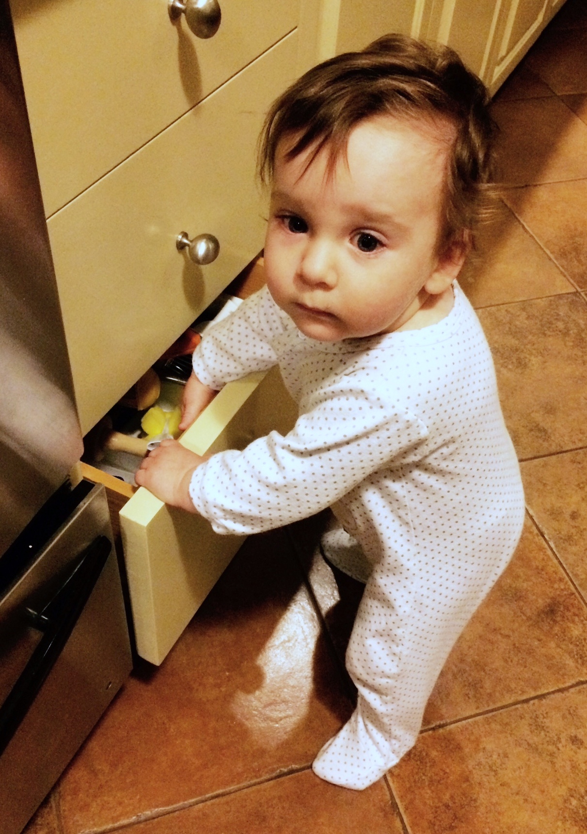 a little child playing with food in the kitchen