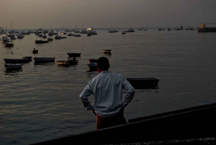 a man looks out at the water while standing in front of a harbor with boats