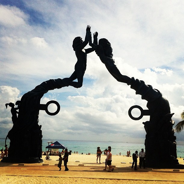a statue of a person holding hands is on the beach
