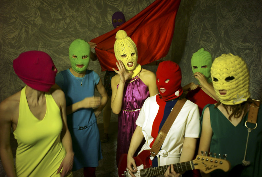 group of masked people in a group with one woman on guitar
