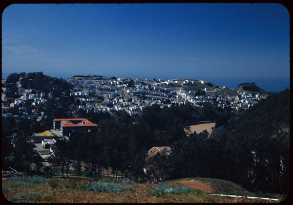 a city sits above trees and hills on a hillside