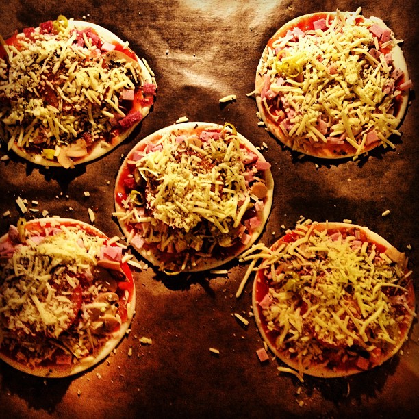 a close up of four small pizzas covered in cheese