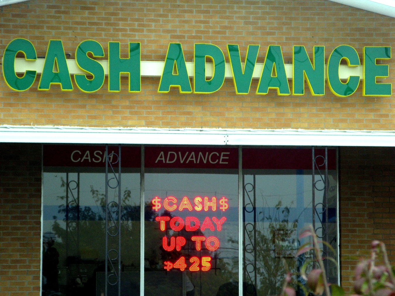 a sign advertising cash advance sits in the window of a bank