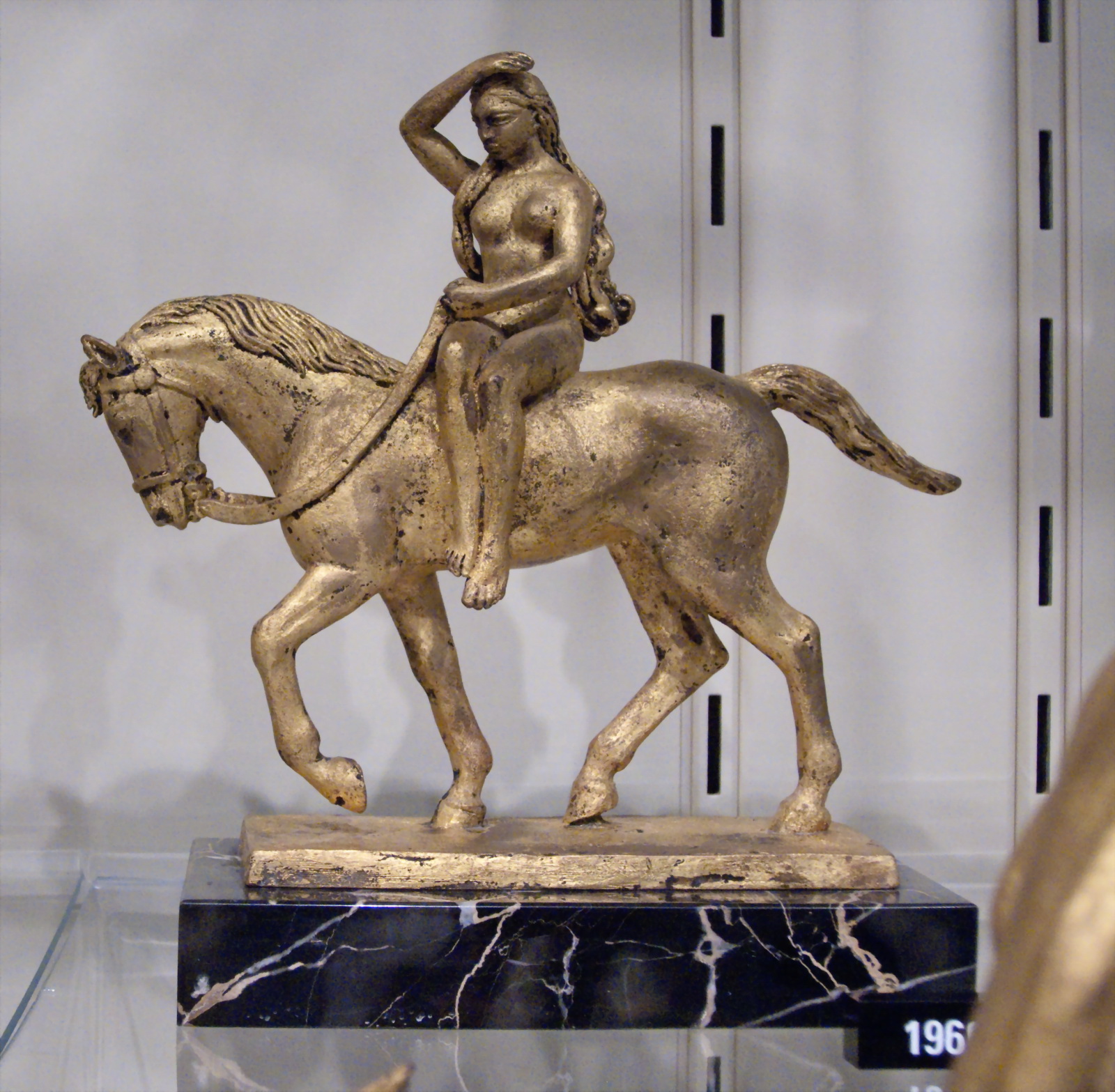 a statue of a woman riding a horse in a glass case