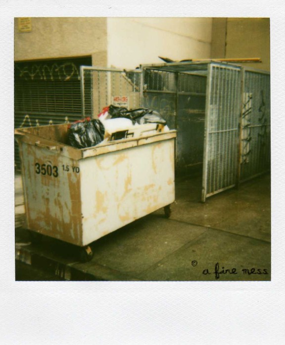 a old po with old garbage cans, crates, and a fire escape