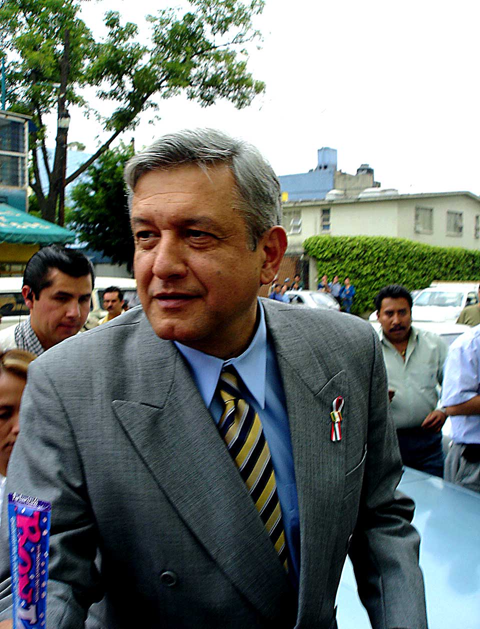 a man in a suit walks past a blue car with a gold stripe tie