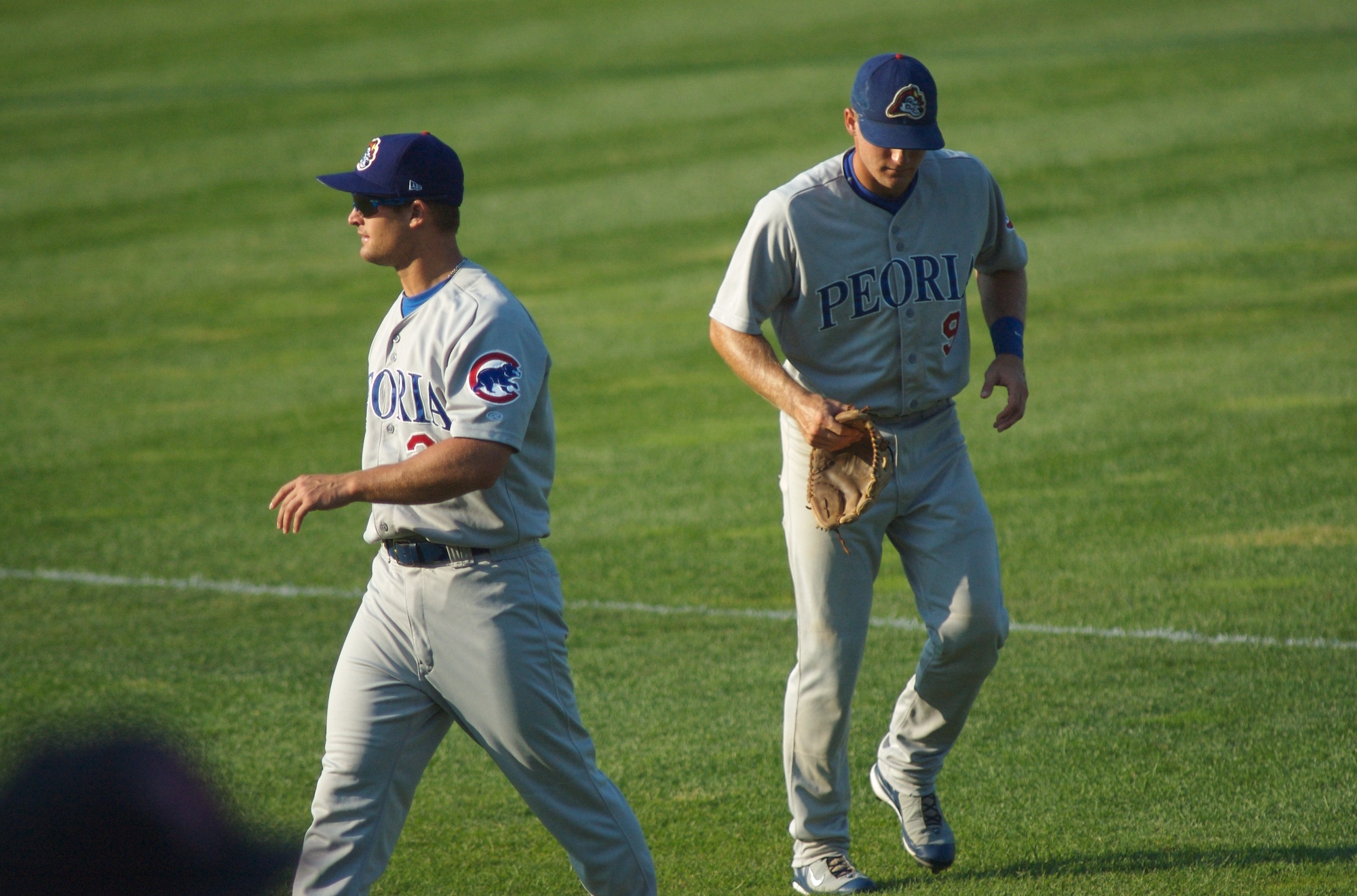 two baseball players with blue and grey uniforms are on the field