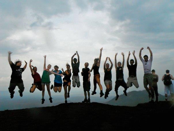 people jump in the air on a mountain near water