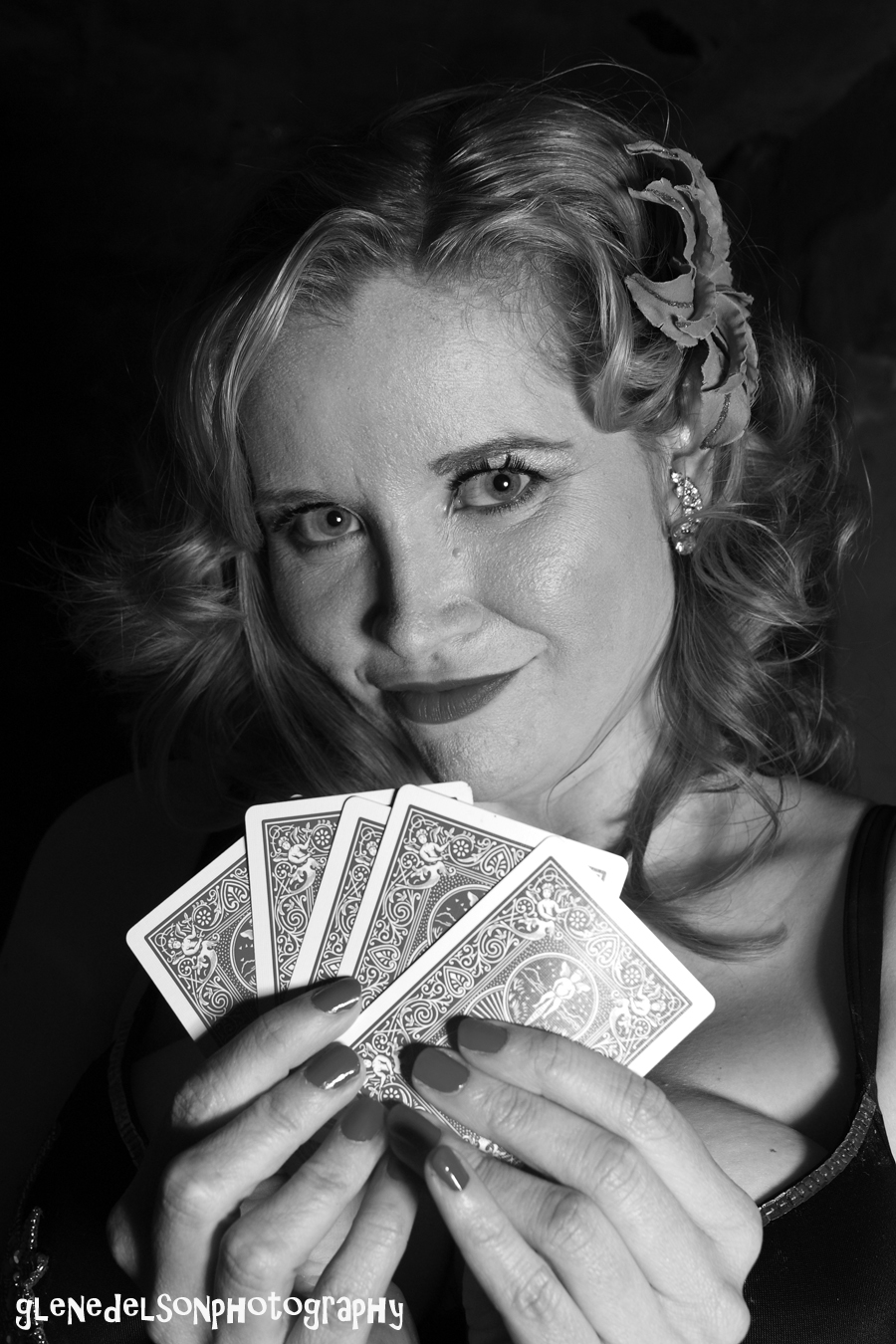 black and white pograph of a woman holding four of a kind of playing cards