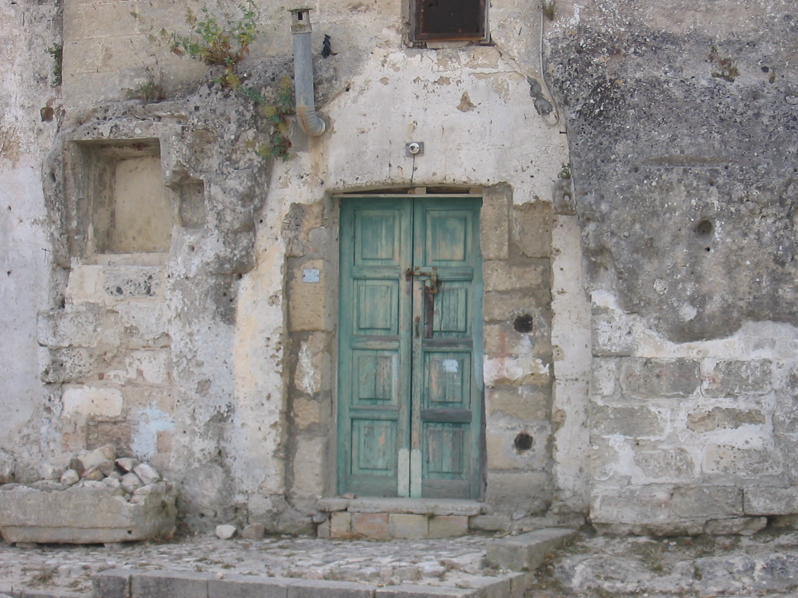 a stone building with a green door and window