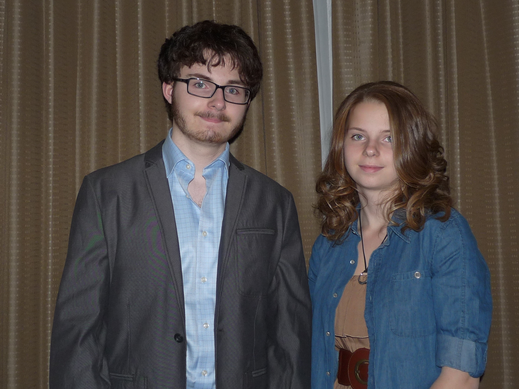 two people posing for a picture together in front of a curtain