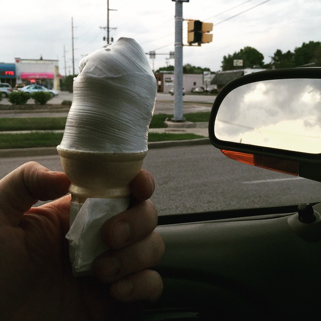 the hand holds a large, crumpled ice cream cone
