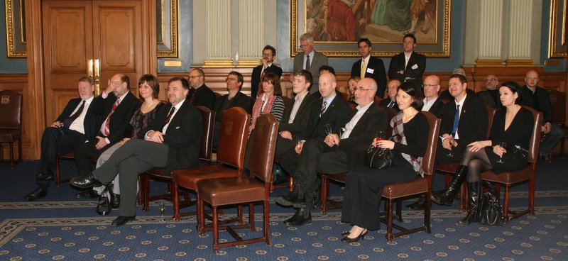 a group of well dressed men and women seated in chairs
