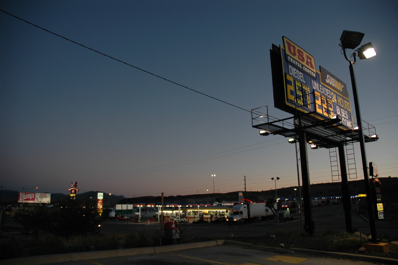 a billboard hangs over the parking lot at dusk