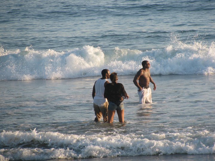 a group of people standing in the water on the beach