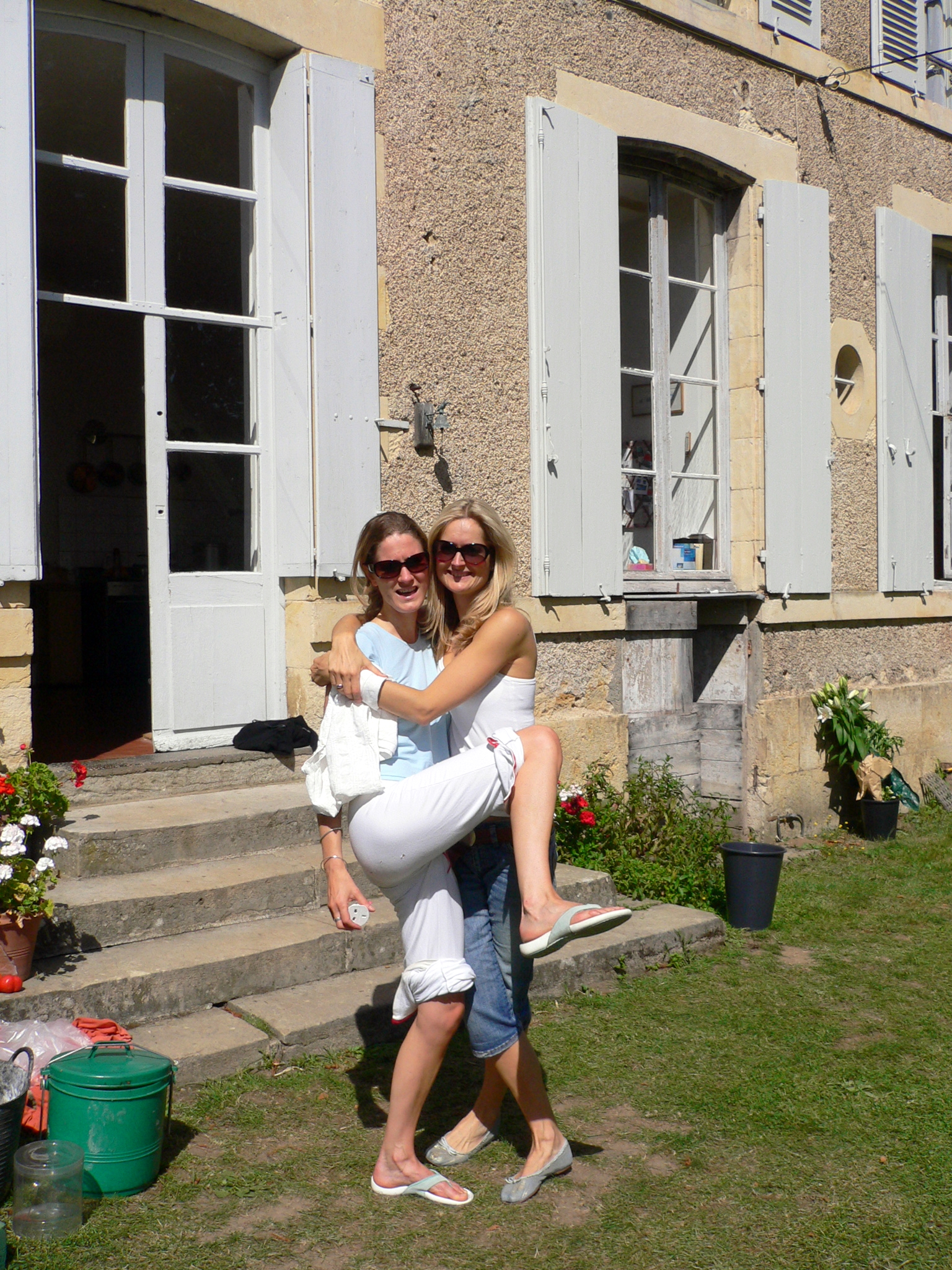 two women outside a large brick building holding an infant