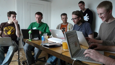 group of people with laptops sitting at desks in room