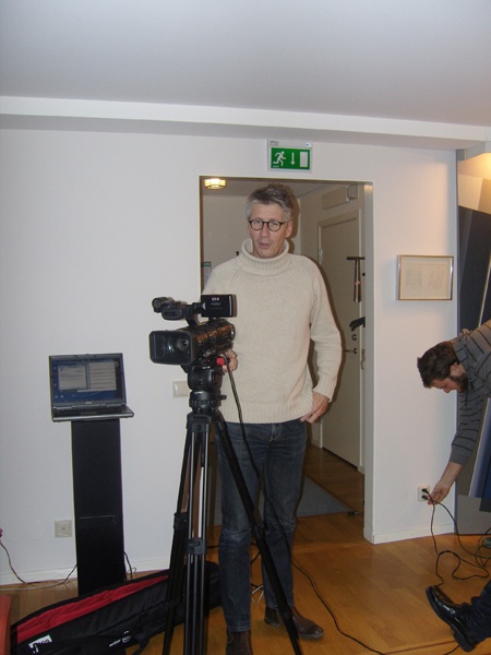 two men are filming themselves in a small room