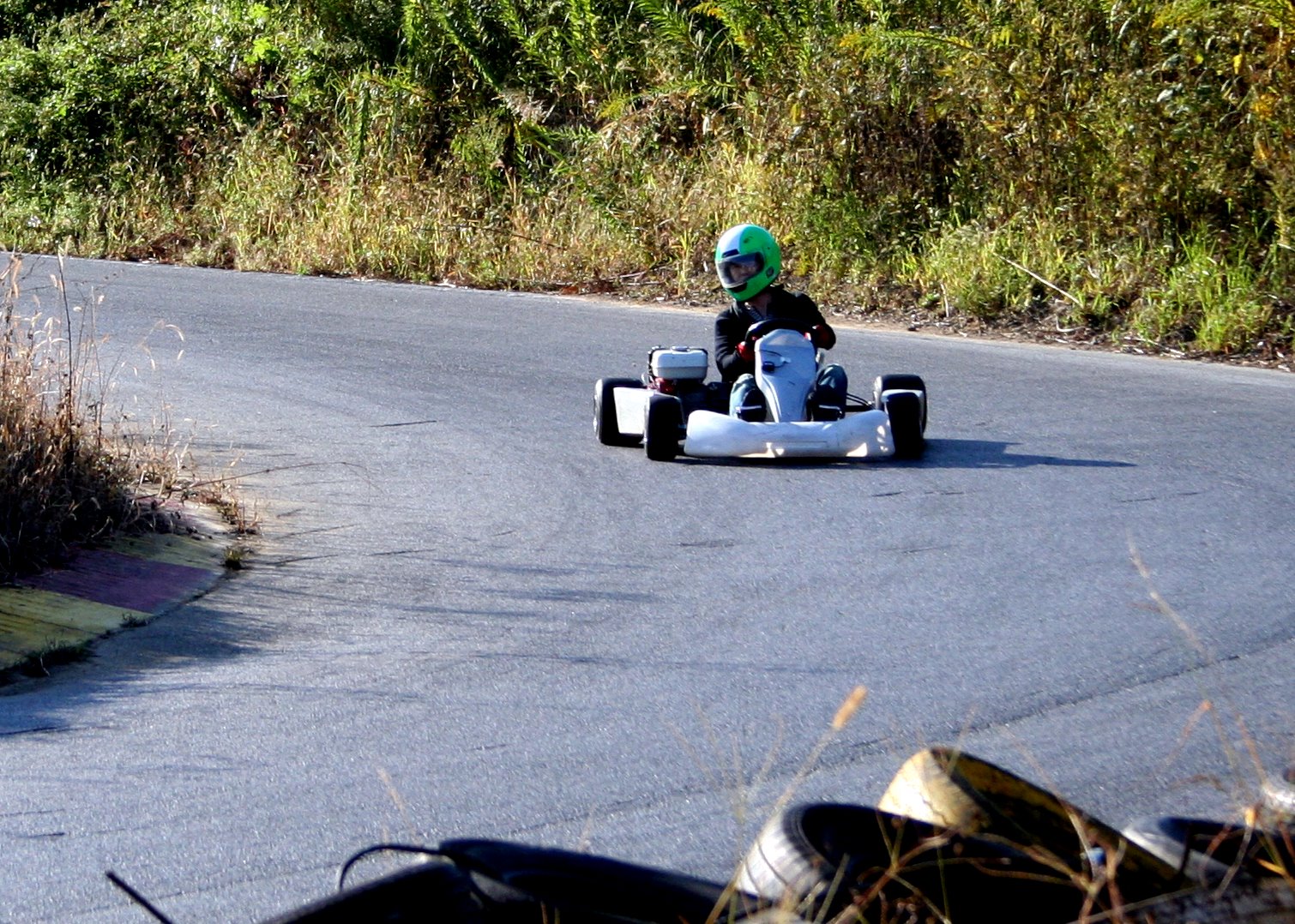 a small boy driving a go kart down a country road