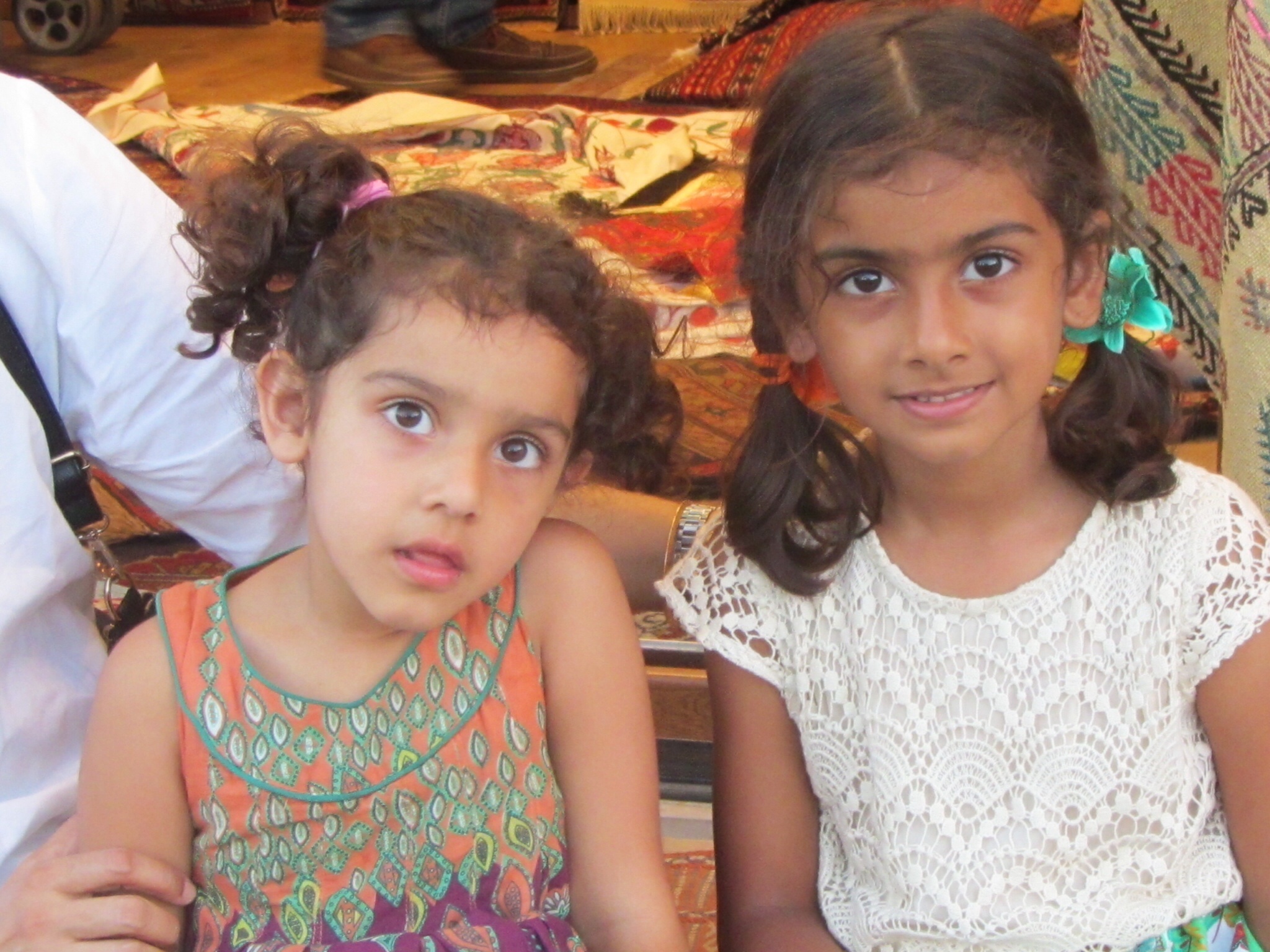 two girls sit side by side while one girl sticks her tongue out