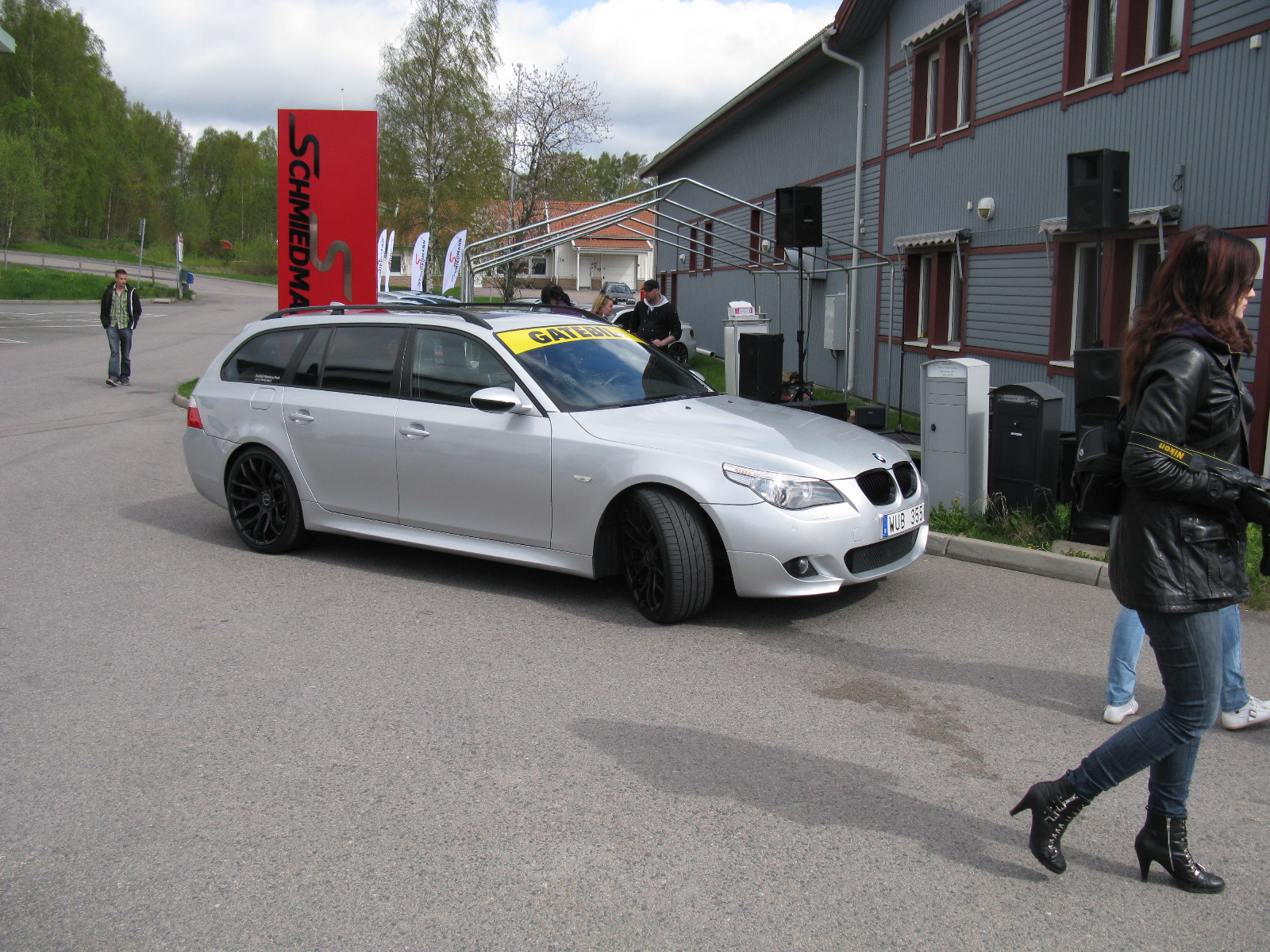 a woman walking down a street next to a white car