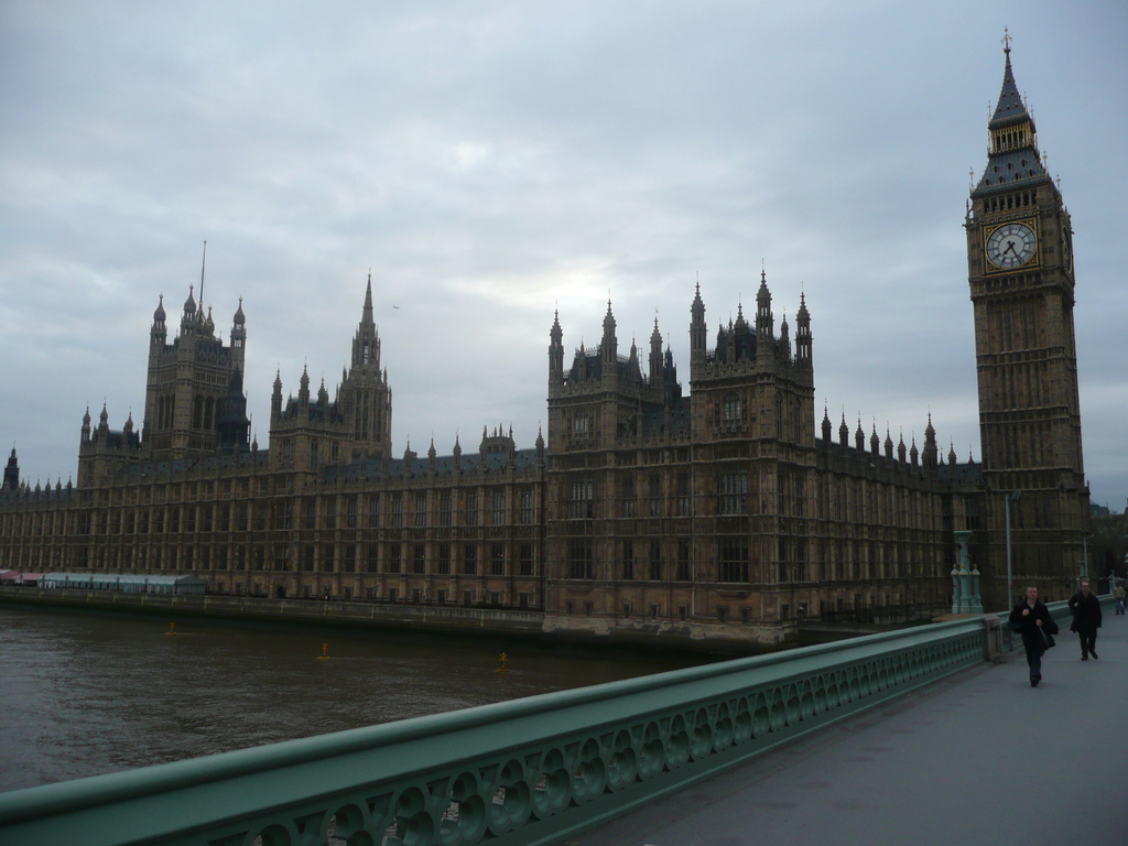 large brown clock tower in city near river