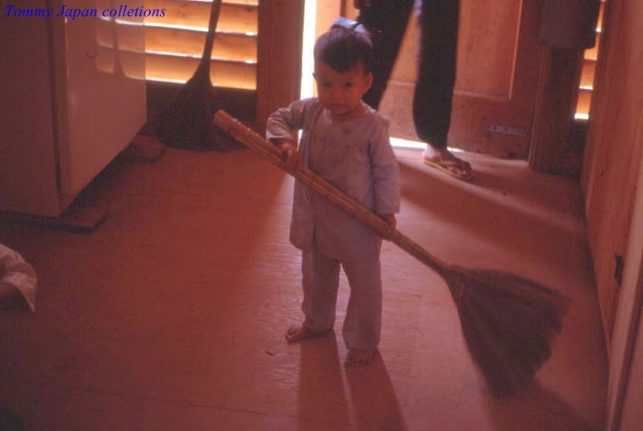 a young child holding a broom while standing in front of people