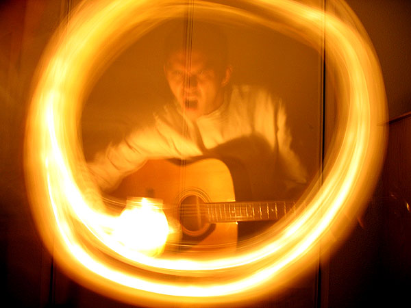 the man plays a guitar while glowing yellow circles are around him